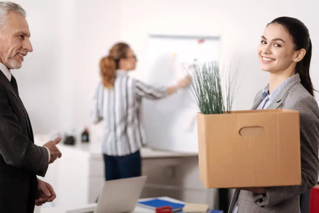 A smiling professional in a new office setting, symbolizing a successful career transition after receiving outplacement support.